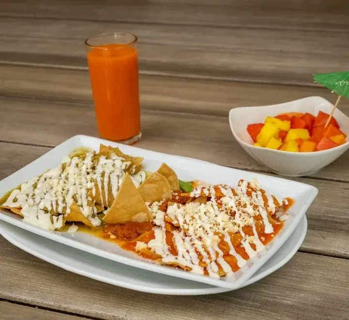 Plato de chilaquiles con salsa, crema y queso fresco
