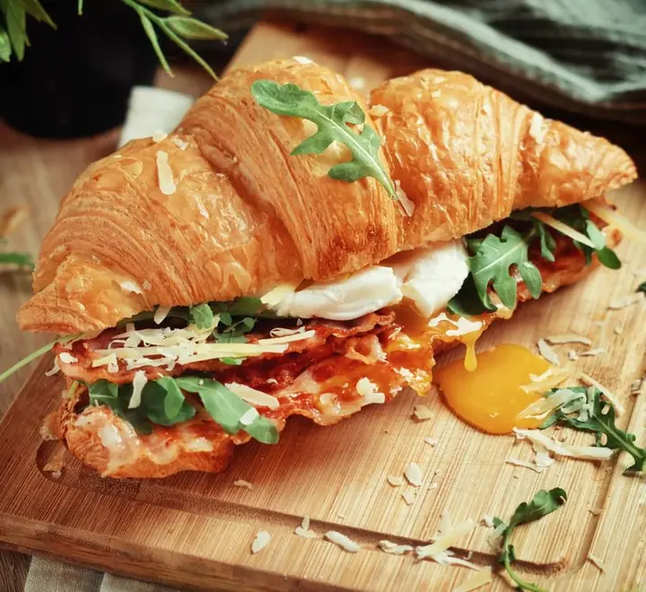 Sándwich de croissant relleno de huevo y hojas verdes