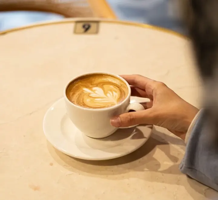 Latte con arte en la espuma servido en taza de cerámica