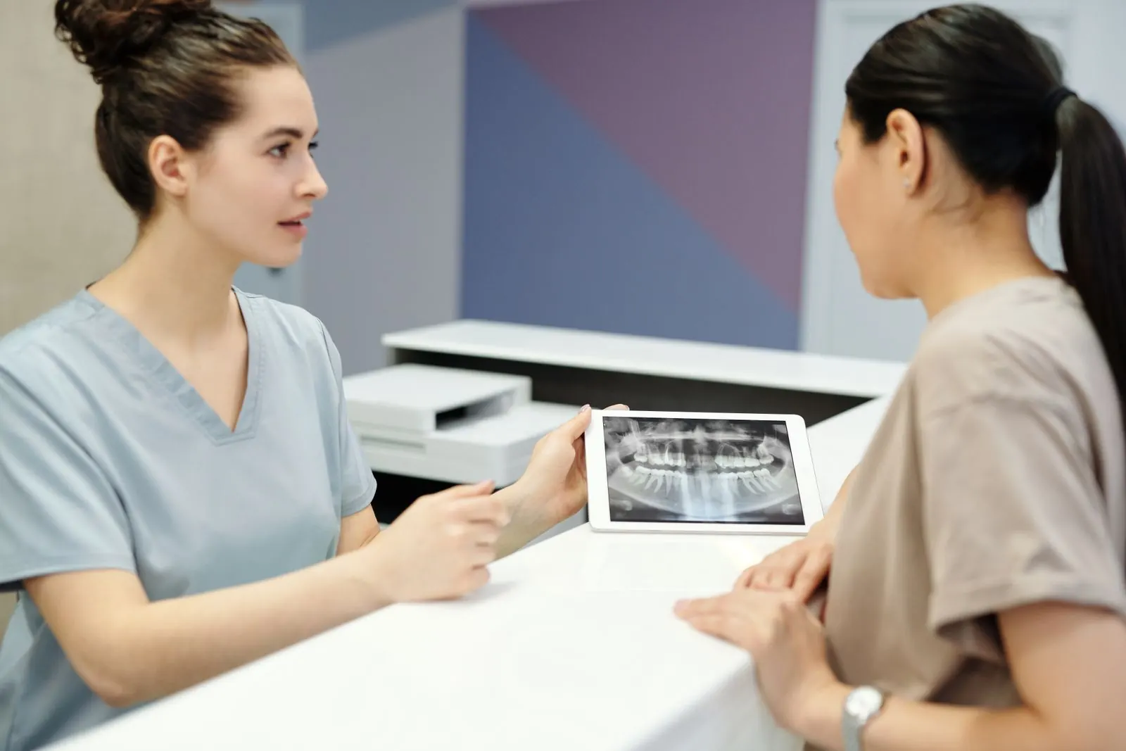 Dentista explica una radiografía dental a una paciente durante una consulta