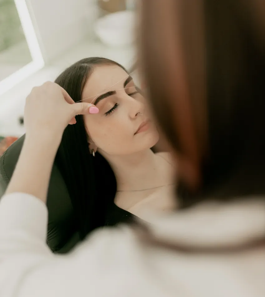 Especialista trabajando las cejas de una clienta